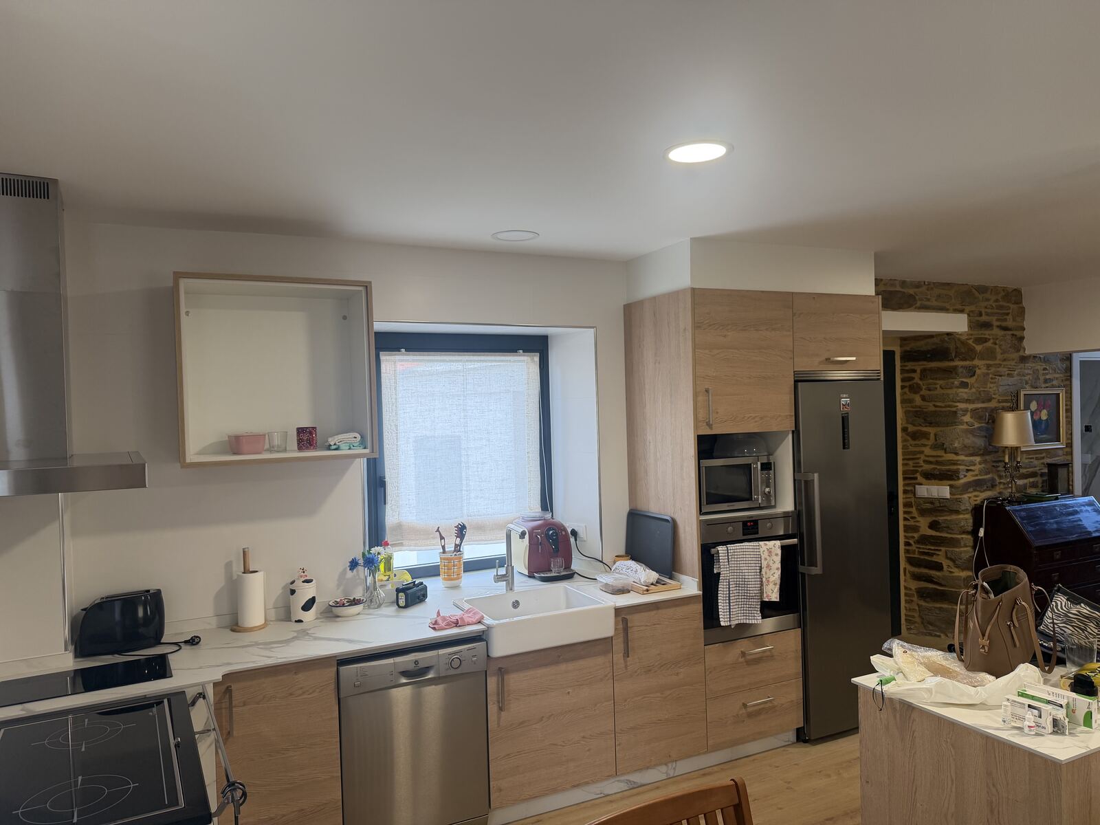 Cocina de madera clara con electrodomésticos en acero